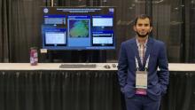 Yasin Chowdhury standing in front of his research poster at AAS.