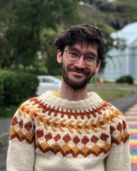 Photo of Pip Petersen in Iceland front of rainbow road and blue church.