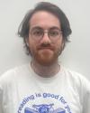 picture of white male, brown hair, glasses, bear, t-shirt that says "reading is good for you"