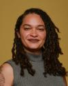a professional headshot / portrait of Arianna with a yellow-gold background