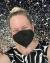 Selfie of Jessica Ness, a white woman with blonde hair pulled into a bun on top of her head. She is wearing a black and white top and a KN95 mask over her smiling face. 