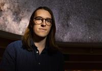 Max Frissell in the UW Planetarium, with the starry "sky" visible behind him.